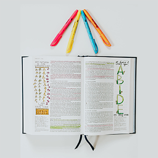 Open Catholic journal bible with notes, drawings, doodling, pens, and colorful, highlighted text